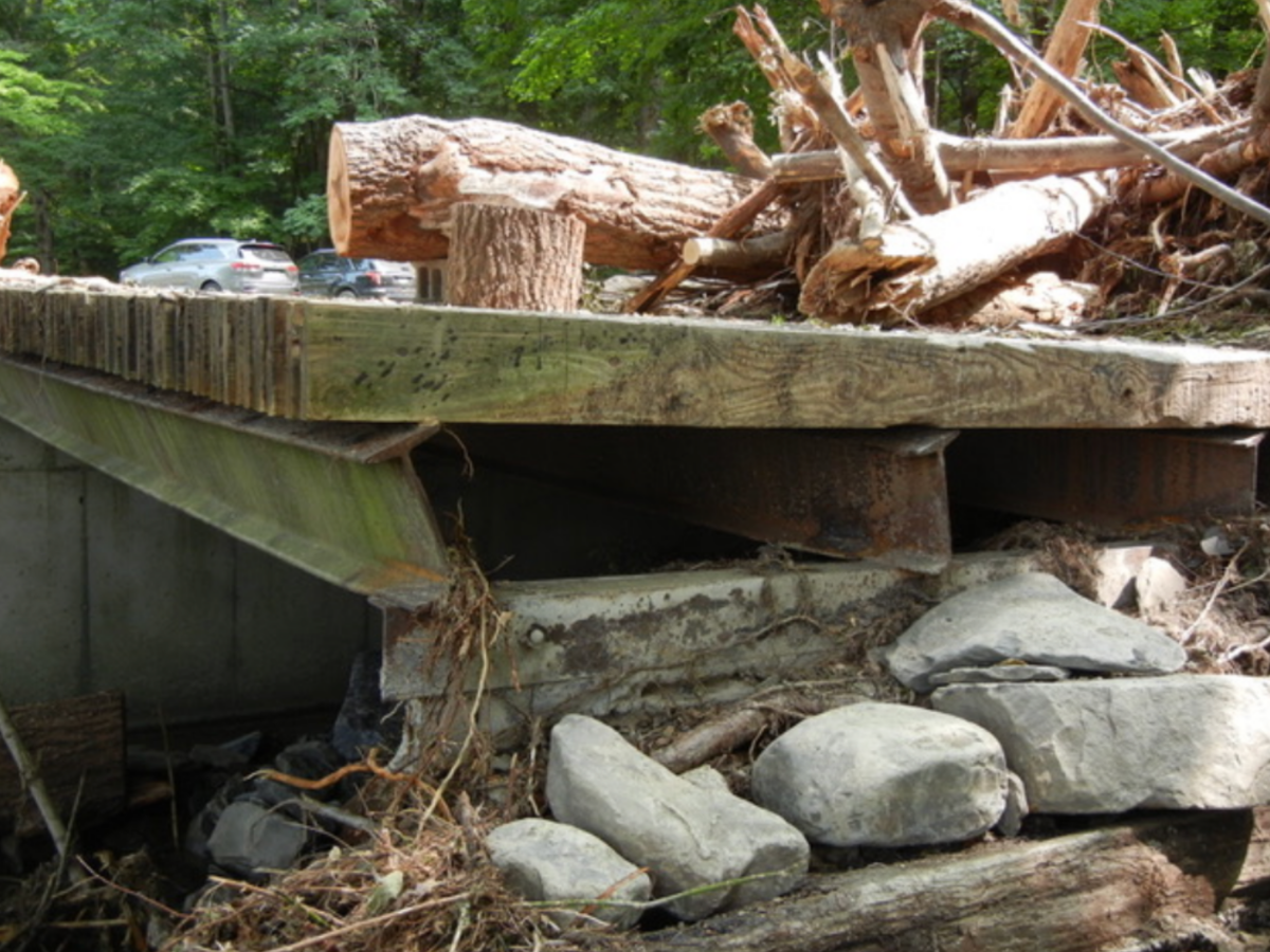 Photo captured by Charlie Fausold — A fallen hemlock became lodged behind a bridge abutment during the August 2018 flooding, blocking the creek and diverting water across nearby land, contributing to significant damage in the neighborhood.
